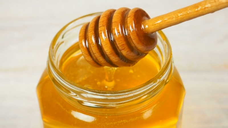 Tegla sa zlatnim medom i drvena kašika za med iznad otvora